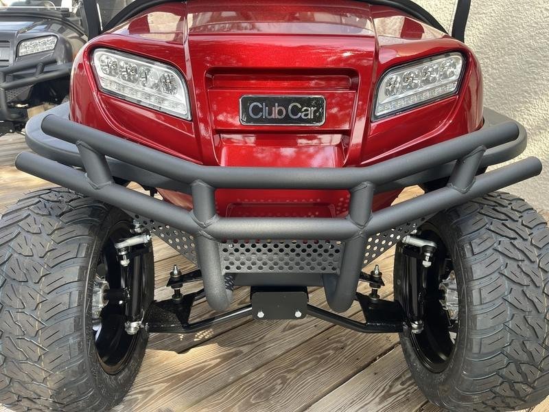 Front of a red Club Car Onward Lifted with brush guard and all-terrain tires
